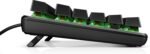 Low-angle view of a black mechanical keyboard with the green PCB visible under the keys and a wired connection.",