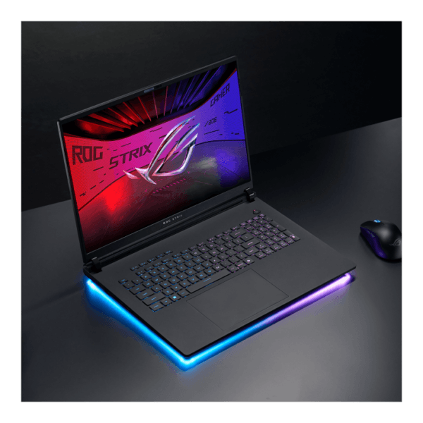 Gaming laptop with RGB-lit base and neon keyboard, open on a dark desk with a wireless mouse nearby (ROG Strix logo on screen).