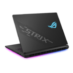 Gaming laptop seen from the back-left with RGB underglow lighting (pink to blue) and a blue ROG logo on the lid, angled open view.