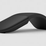 Black wireless ergonomic mouse with a curved, hinge-like design on a light gray background for comfort-focused use imagery.