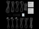 Bundle of black PC power cables, connectors, and brackets laid on a black background, with two white information booklets and a desiccant packet nearby.