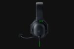 Black over-ear gaming headset with attached microphone and green accents on a dark background.