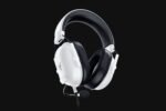 White over-ear gaming headset with a mic, black padding, and logo on the ear cup against a dark background.