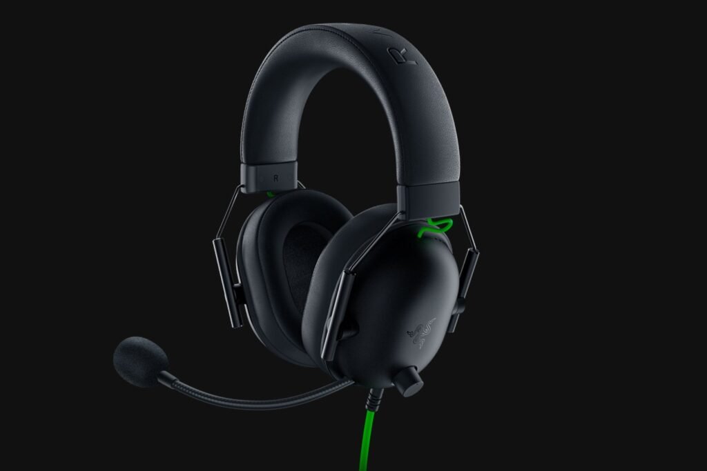 Black over-ear gaming headset with attached mic on a dark background, wired with a green accent cable (Razer branding). Popular for immersive audio.