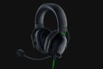 Black over-ear gaming headset with attached mic on a dark background, wired with a green accent cable (Razer branding). Popular for immersive audio.