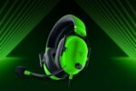 Neon green gaming headset with mic and black ear cushions against a dark green stage backdrop.