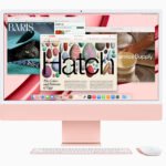 Rose‑gold iMac with keyboard and mouse on a pink background; screen shows multiple windows and colorful imagery.