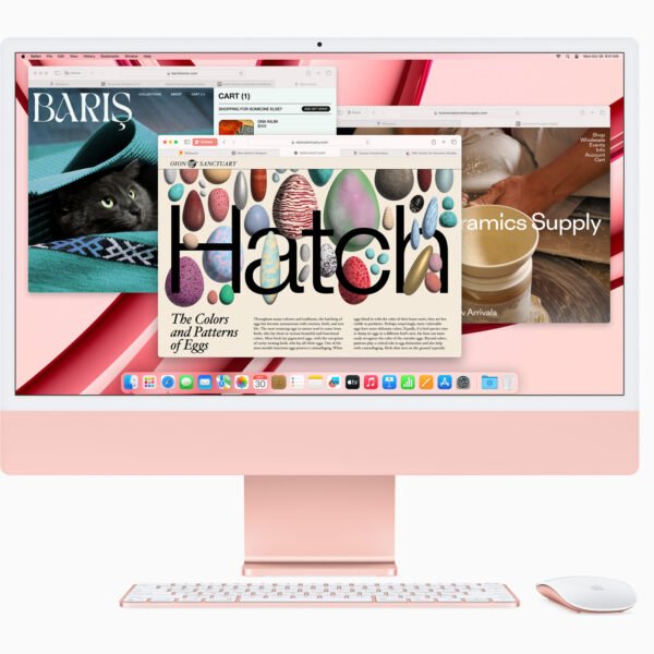 Rose‑gold iMac with keyboard and mouse on a pink background; screen shows multiple windows and colorful imagery.